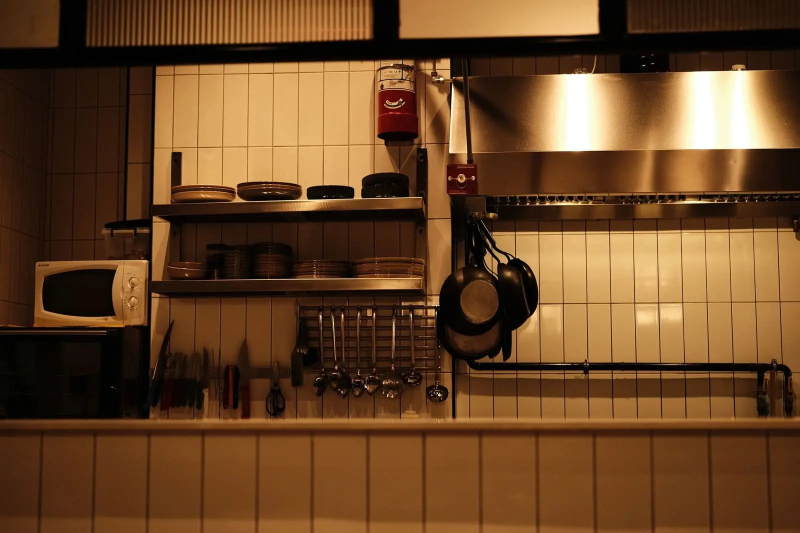 Hotte d'extraction inox et étagères d'une cuisine de restaurant carrelée, illustration Biohotte Nuisibles, Nanterre